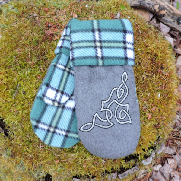 Pair of mittens with tartan pattern and Celtic knot design on a mossy rock.