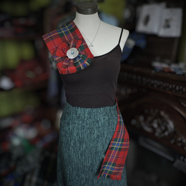 Mannequin wearing a black top and green skirt with a red plaid accessory in a store setting